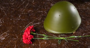 anıt mermer levha üzerinde orada iki karanfil ve askeri headdress, kask