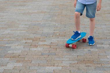 Bir çocuğun ayak yakın çekim bir spor yönetim kurulu bir taş fayans ustası, arka planı mavi spor ayakkabılar üzerinde duran bir yazıt için bir yer var.