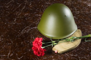 iki kırmızı karanfil, bir askeri şapka ve bir kask, anıtın arka planda, yazıt ölümsüz alay için bir yer var