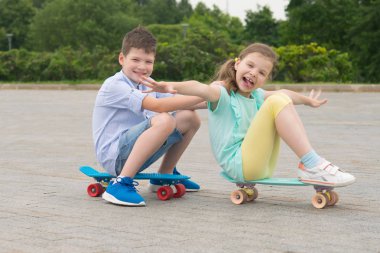 park açık havada kız ve erkek, spor tahtaları üzerinde oturan sürme, komik grimaces bina