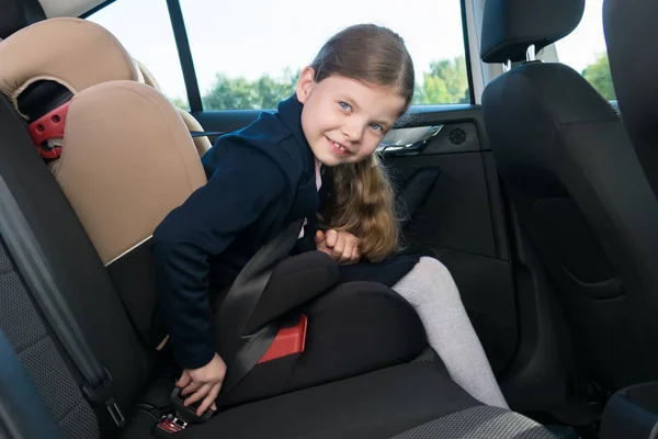 the girl in the car before going to school fastens the seat belt of her seat