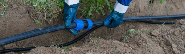 Manos Guantes Azules Protectores Sostienen Una Tubería Agua Una Trinchera — Foto de Stock