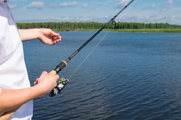 クローズアップ 釣り竿と釣り用のフックを持つ男 青い湖に対して — ストック写真