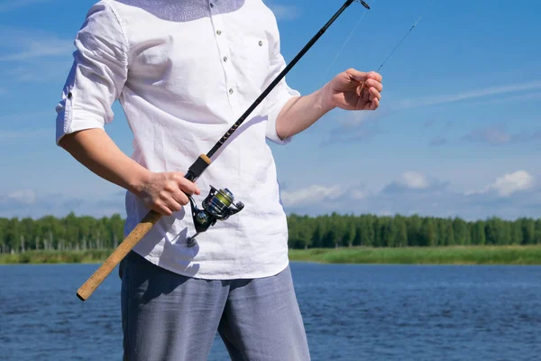 クローズアップ 男の手は 湖の背景に対して 魚とフックをキャッチするための釣り竿を保持します — ストック写真