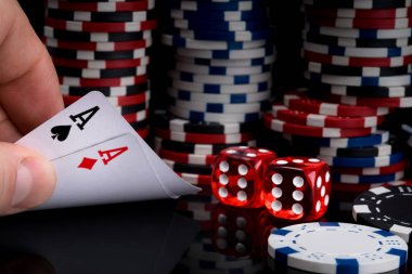 bir poker oyuncusu kırmızı zar yanında poker fişleri yığınları arka plan karşı siyah bir tablo üzerinde yükselterek onun kartları bakar
