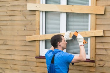 adam pencerede tahtalar içine çivi tekmeler, kasırga onu kapatır