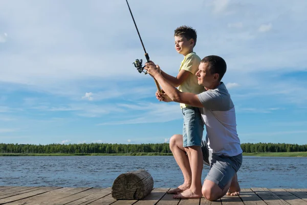 父は家族の休日に湖で回転する上で魚に息子を教えます — ストック写真