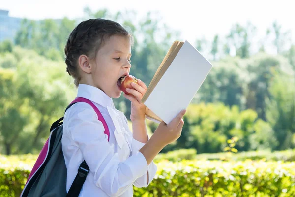 Schulmädchen Isst Einen Apfel Und Liest Ein Buch Auf Dem — Stockfoto