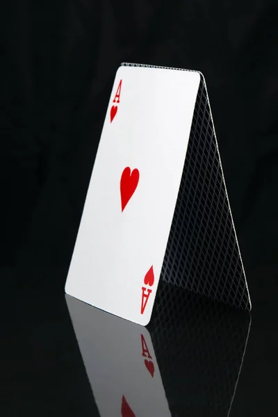 card for a poker game, stands a pyramid, on a black background with reflection, close-up