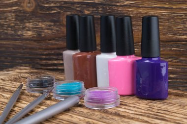 ahşap bir arka plan üzerinde, çok renkli vernikler bir satır ve rhinestones kavanoz içinde kendi uygulama için fırçalar ile tırnak dekorasyon için düzenlenmiş