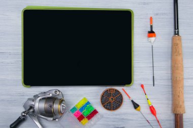 hafif bir arka planda, tabletin siyah ekranında, balıkçılık, yüzer, balıkçı hattı, platinler için nesnelerin yakınında, uygulamalar ve yazıtlar için bir yer vardır