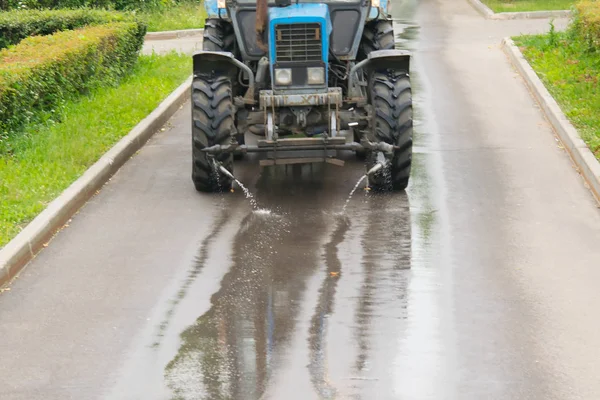 in the recreation Park, a watering machine moistens the asphalt to clean the road