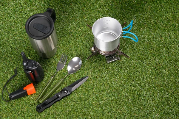 On a green lawn, a traveler's set, a walkie-talkie, a lantern, a fork, a spoon, a gas burner, a knife, a thermos, there is a place for an inscription — Stock Image Green Lawn Traveler Set Walkie Talkie Lantern Fork Spoon Gas Stock Picture