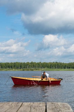 Ahşap bir teknede bir adam o bir olta ile yakaladı sudan bir balık çeker