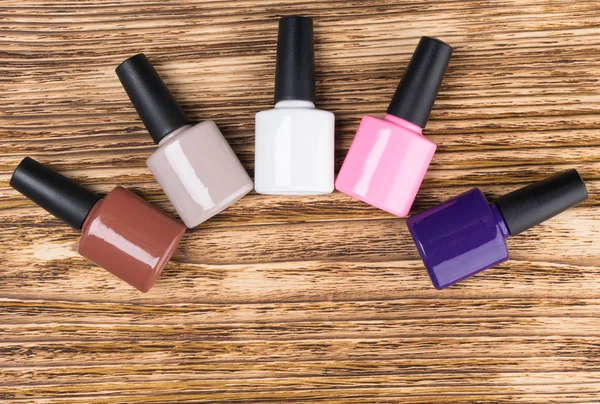 set of multicolored gel polishes for manicure and pedicure lies on a wooden background