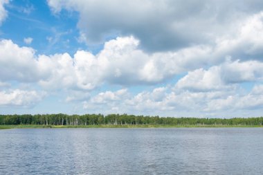 ormanda gölün üzerinde beyaz bulutlar ile mavi gökyüzü