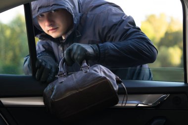 Siyah ceketli bir adam bir araba penceresinden belgelerle bir kadın deri çanta çaldı