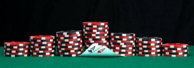 yeşil bir masada, poker oynamak için, farklı renklerde fiş piramitleri ve iki yükseltilmiş kartları, aslar, yazıt için siyah bir arka plan üstüne