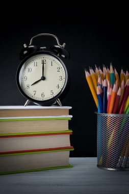 tablonun karanlık bir arka plan üzerinde okulda çalışmak için nesneleri ile saat