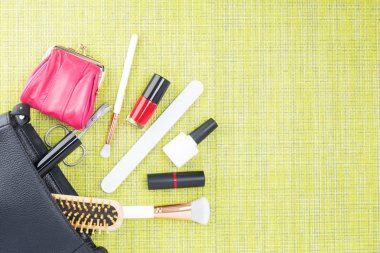 yeşil bir arka plan üzerinde dağınık siyah bir kadın çanta kozmetik