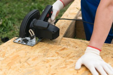 adam bir testere ile kontrplak bir parça keser, yakın çekim