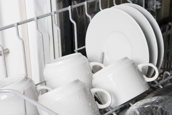 close-up of clean plates and mugs on the grill of the dishwasher