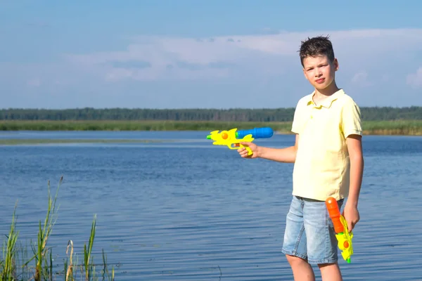 Jongen Achtergrond Van Een Blauw Meer Hemel Spelen Waterpistolen — Stockfoto