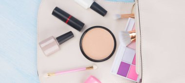 hafif bir arka plan üzerinde, beyaz bir kozmetik çantası, manikür ve makyaj için dağınık öğeler, renkli göz farı, fırçalar, yüz tozu, oje ve ruj, yazıt için bir yer ile