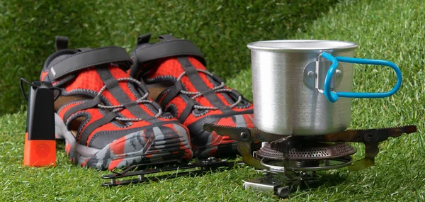 on a green lawn, a traveler set, close-up, comfortable sneakers, a flashlight and a gas burner