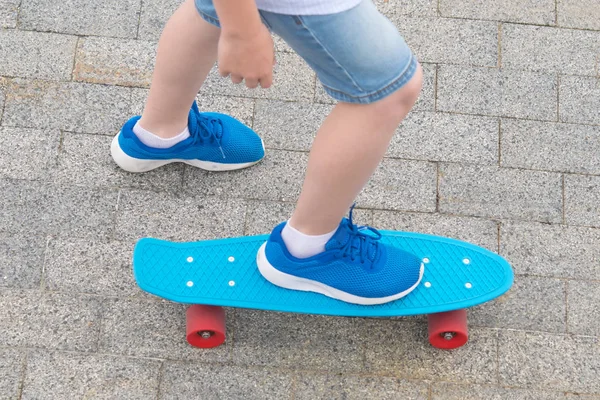 on the blue sport chalkboard, closeup, foot baby blue sports shoes, rides on the stone pavement of the