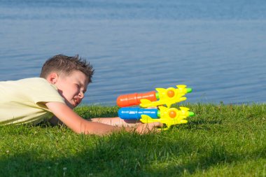 çocuk, güzel bir manzara arka planda, bir su tabancası ile oynarken, hedefe ayarlar, yakın çekim