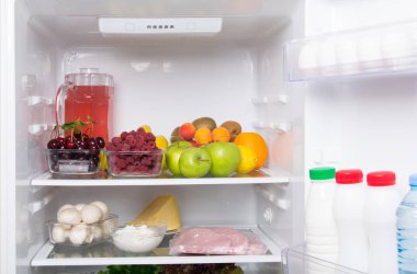 beyaz bir buzdolabında, üst rafta meyve, çilek ve komposto ile bir sürahi, alt mantar, süzme peynir, peynir, yumurta ve kapı süt ürünleri, kefir, krem ve su vardır