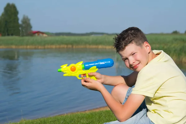 Jongen Achtergrond Van Een Prachtig Landschap Spelen Met Een Waterpistool — Stockfoto