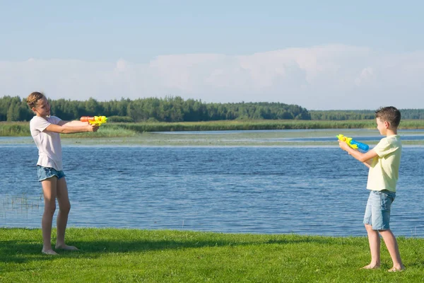 Niño Niña Lago Hierba Verde Jugando Con Pistolas Agua Apuntándose — Foto de Stock