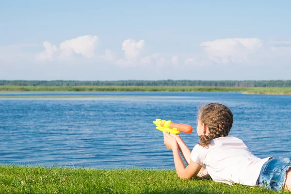 Menina Está Deitada Grama Verde Brincando Com Uma Pistola Água — Fotografia de Stock