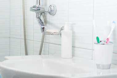 lavabonun banyoda diş fırçaları ve bir macun ile bir cam var