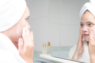 ayna önünde banyoda duran bir bornoz akne bakım genç