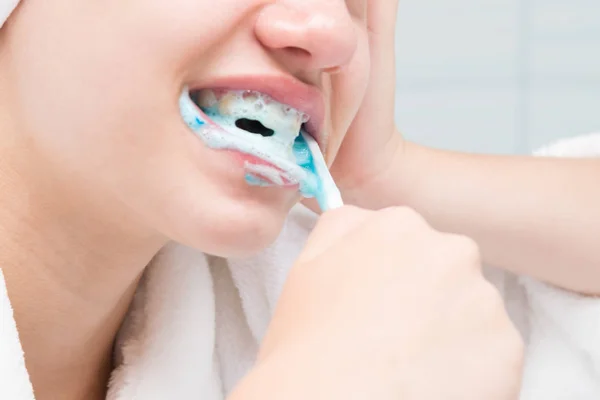 close-up of face and hands with teeth cleaning toothbrush