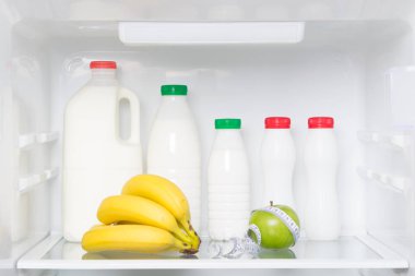 beyaz buzdolabı, yeşil elma, muz, vücut ölçüm bandı ve süt ürünleri, kefir, krema, yoğurt rafına