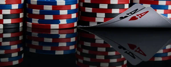 close-up, a set of pyramids of poker chips and two highest cards, on a black background with reflection