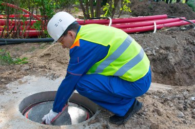 beyaz kask ve mavi üniformalı bir işçi, iletişim için manifoldun kapağını kapatır