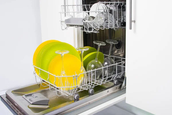 two loading nets, filled with wet plates, mugs and glasses, after rinsing, in the dishwasher