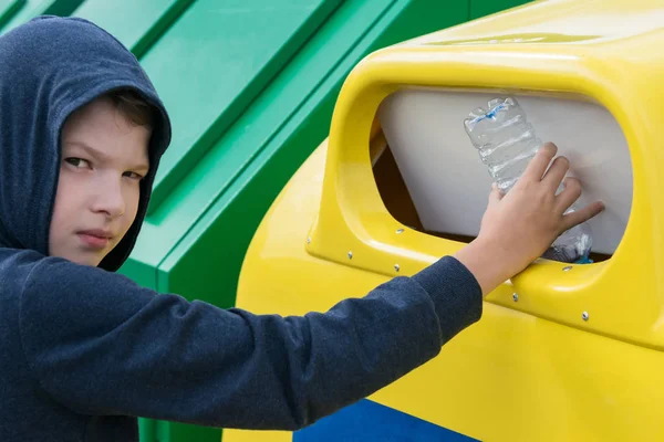 çocuk ayrı çöp toplamak için bir konteyner içine boş bir plastik şişe atar