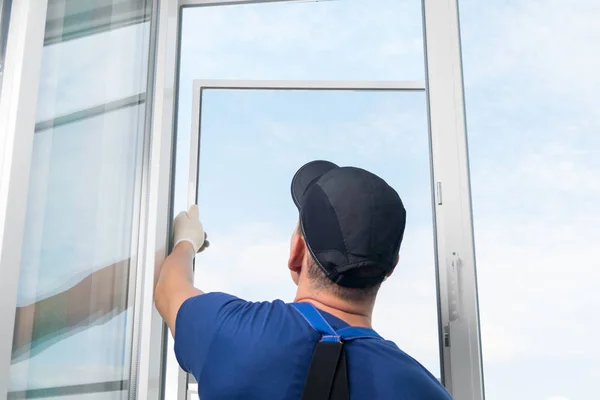 the master installs a mosquito net from insects in a new plastic window