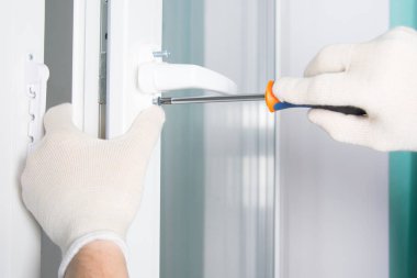 işçilerin koruyucu eldiven eller, plastik pencereye bir tornavida ile kolu vida