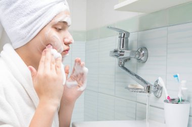 banyoda lavabonun önünde dururken kız yüzünü yıkama