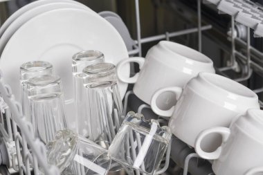 beyaz kahve fincanları ve tabaklar bulaşık makinesi sepetinde