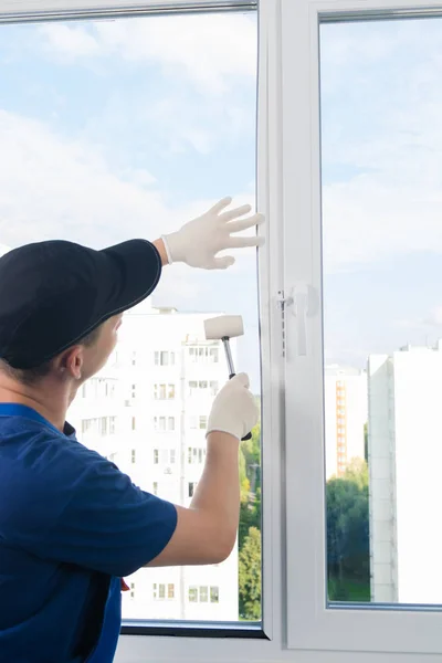plastic window installation wizard fastens glass with a rubber mallet
