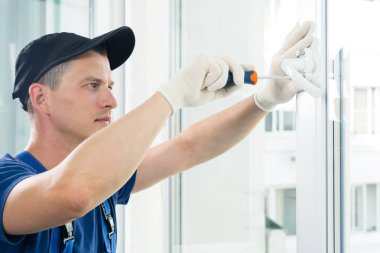 bir işçinin elleri plastik bir pencereye sapı bağlamak, yandan görünümü