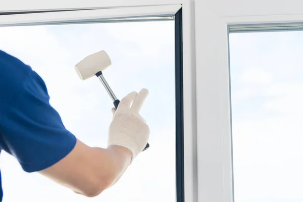 worker fixes a double-glazed window in a frame of a plastic window